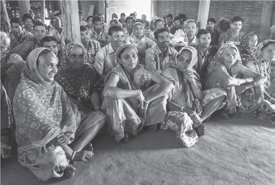 Image of many Indians sitting on the floor in a room.