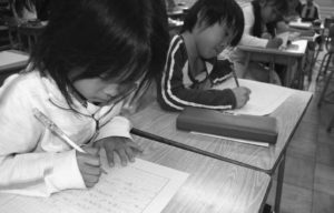 Two Japanese students doing homework at their school desks. 