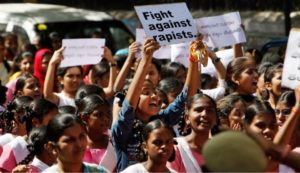 Image of crowed doing protest with the slogan fight against rapists