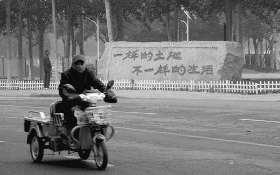 A man contemplates the slogan “same land, different life” on the boulder at the entrance of Huaming’s wetlands park while another man drives by on an electric bicycle. Source: Photo courtesy of the author.