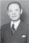 A portrait of a middle-aged Ho Fengshan, dressed in a Western-style suit and tie. The image showcases his professional attire, reflecting his role and presence in a contemporary setting.