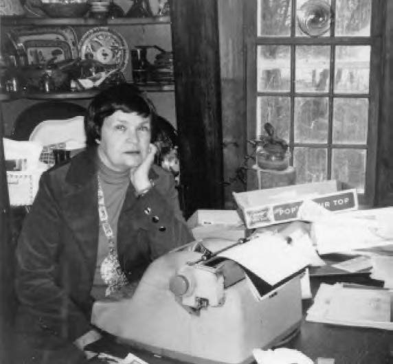 a middle aged woman poses with her typewriter