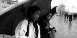 Screen capture of two girls holding umbrella