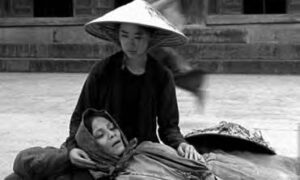 photo of a woman in a straw hat holding a woman as she dies