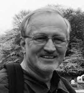 A head-to-shoulder photograph of Jim Huffman, a middle-aged man. He is wearing glasses and has a joyful smile on his face.