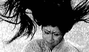 an image of a woman in white with exaggerated makeup, her long black hair flying up and around her.
