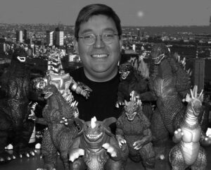 photo of a man smiling with many godzilla toys