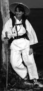 photo of a woman in a white gi and a walking stick