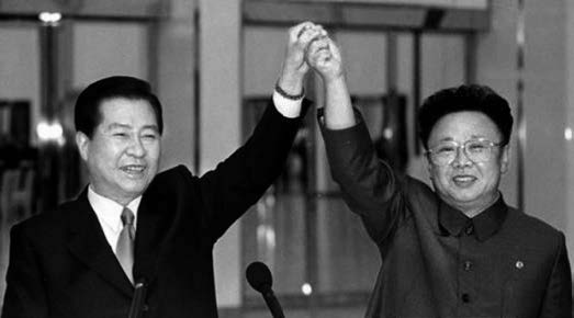 Former president of South Korea, Kim Dae-jung holds Kim Jong Il's hand in the air in a show of solidarity. Photo taken in 2000.