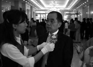 a woman adjusts the flowers on his lapel