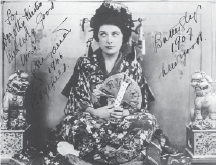 Signed photo of a woman in traditional Japanese dress sitting holding a fan