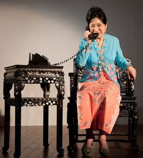 a photo of a woman sitting and making a phone call on a rotary phone