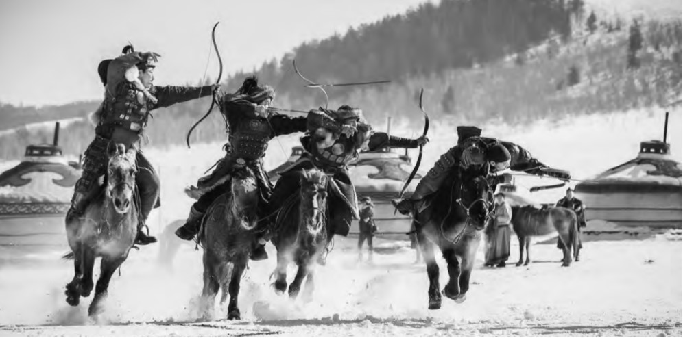 photo of men shooting arrows off the back of their horses