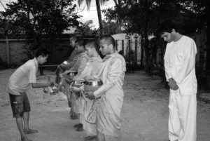 A student bows to a line of Cambodian monks. 