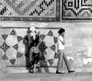 A photo of a woman walking by many intricate designs of a shrine. 