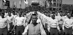 photo of rows of men in the same white shirt and black pants, all wearing white headbands with red circles on them