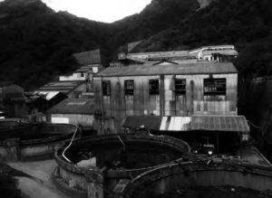 Building ruins of a old copper mine settled amongst a mountainous landscape. 