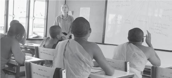 a teacher stands at the front of the room full of monks at desks