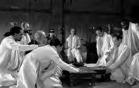 men in white robes sit around a table