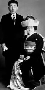 a man stands near a woman sitting for a portrait.