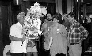 photograph of a man holding an elaborate puppet while viewers look on. 