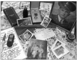 Photo of items on the table, such as some pictures, an envelope, a pen, and a photo of a man. 