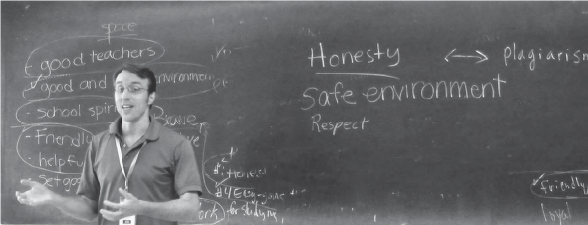 a man speaks in front of a blackboard