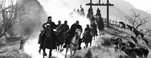 Photo shows some people riding horses crossing among the curving road in hills