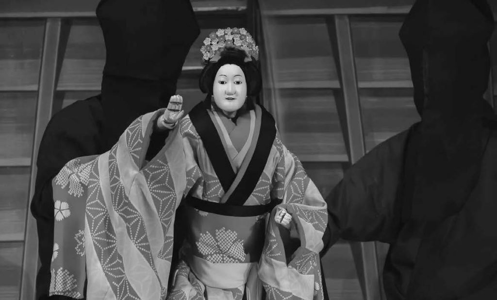 A puppet Bunraku performance in Japan. Bunraku is a collaborative art synchronizing narrative recitation, shamisen music, and puppetry in performance. Noh is a highly sophisticated mask play with a long history. While its sibling, Kyogen, is a comedic, conversational play.