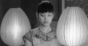 a young woman stands between two paper lanterns