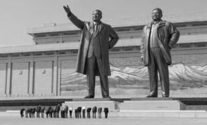 two statues of men stand next to each other. one has his hand outstretched pointing forward