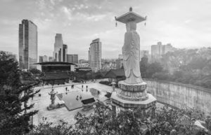 photo from behind a large buddha statue, overlooking a city skyline
