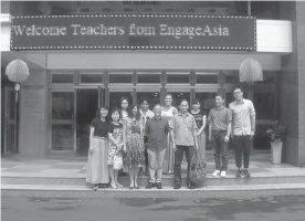 a group of people pose for a photo in front of a sign that reads "welcome teachers from engage asia"