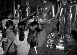 photo of people applying gold leaf to statues of buddha