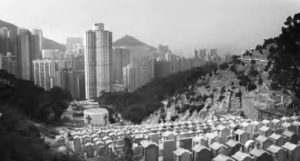 View of Diamond Hill Cemetery with Hong Kong in the background. The gravestones are densely packed and are locate din close proximity to the city highrises. 