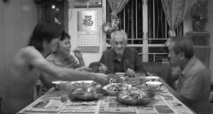 In Hong Kong, Yau King enjoys a meal prepared by his grand-nephew. The group of men smile as they eat.  