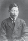 Photograph of a young Sugihara wearing a Western style suit with a stern look on his face. 