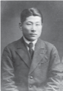 Photograph of a young Sugihara wearing a Western style suit with a stern look on his face.