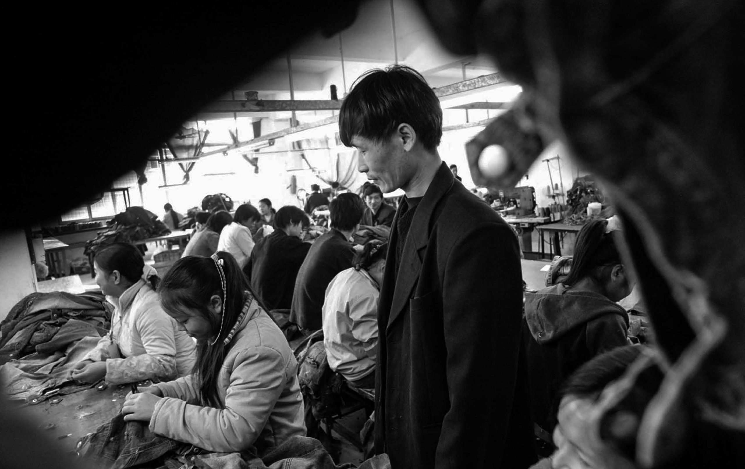 A supervisor keeps a close eye on textile workers during an all-night shift in a China factory.