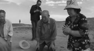 Survivors Chen Zonghai and Xi Xiashan burn joss paper offerings to honor those who died at the camp. 