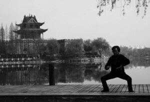 a man does exercise in the park with water and a temple int he background