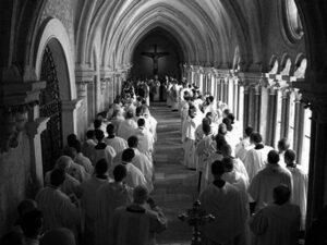 many people in white robes walk down a hallway