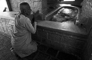 a man in robes kneels and prays
