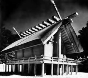 a shrine that sits on stilts with large wooden beams meeting at the center of the angled roof. 