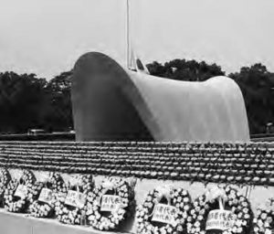 lines of flowered wreaths and memorial flowers can be seen in front of the large curved arch structure. From the side, it resembles a horse's saddle. 