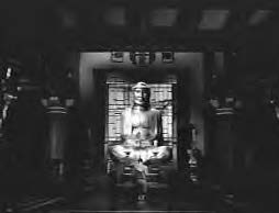 a young boy prays to a buddha statue