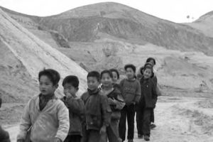 a line of children are seen in front of large plateaus 