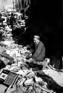 a man sits among goods for sale