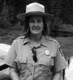 A woman in ranger's outfit and hat smiles. 