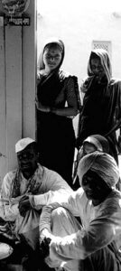 three men sit while two women look on